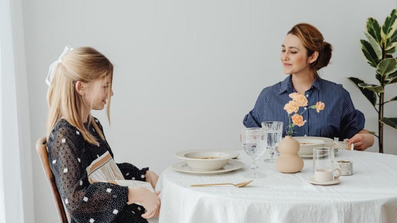 Mother and daughter sharing a happy meal together in a minimalistic dining room setting.